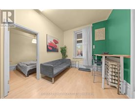 A bedroom with a bed, a chair, and a table with a green wall.