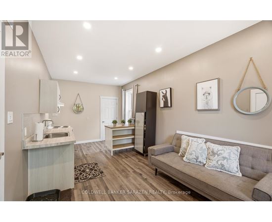 A living room with a grey couch and a kitchen area in the background.