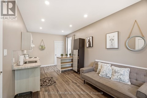 A living room with a grey couch and a kitchen area in the background.
