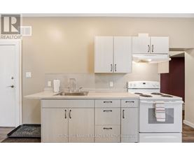 A kitchen with white cabinets and a white stove top oven.