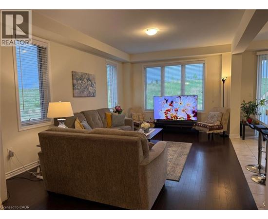 A living room with a couch, a chair, a television, and a painting on the wall.
