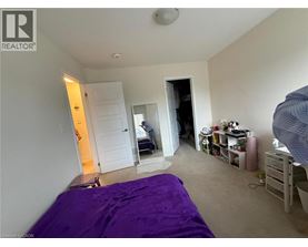 A bedroom with a purple bedspread and a white door.