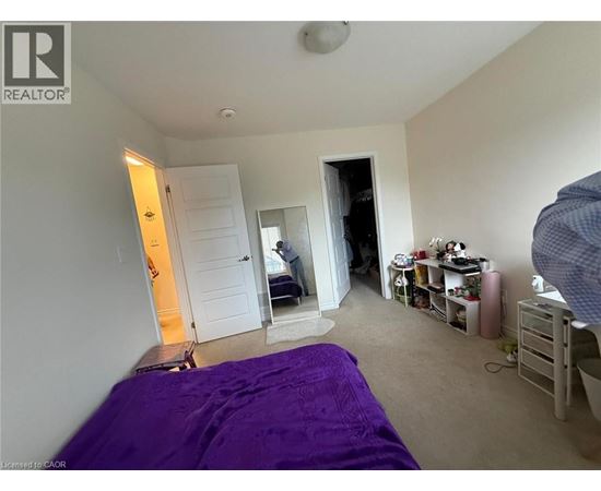 A bedroom with a purple bedspread and a white door.