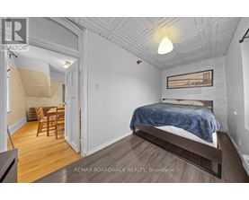 A bedroom with a bed, chair, and table in a white room.