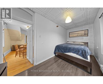 A bedroom with a bed, chair, and table in a white room.