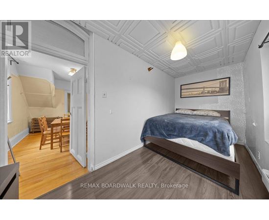 A bedroom with a bed, chair, and table in a white room.