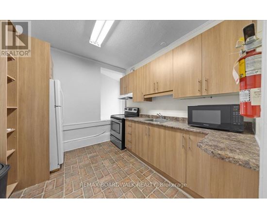 A kitchen with wooden cabinets and a black microwave.