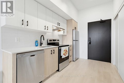 A kitchen with white cabinets and a black door.