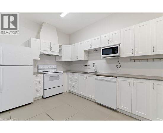 A white kitchen with a refrigerator, microwave, and oven.