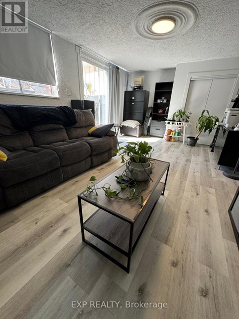 A living room with a grey couch and a glass coffee table.