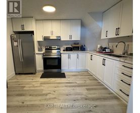 A kitchen with white cabinets and a wooden floor.