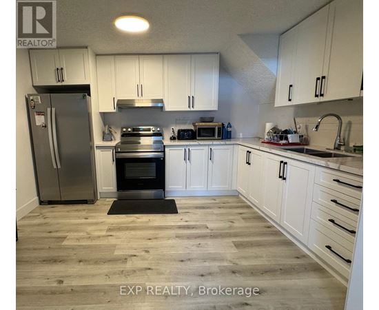 A kitchen with white cabinets and a wooden floor.