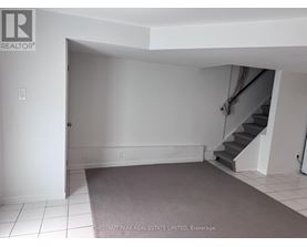 A room with a staircase and a carpeted floor.
