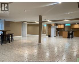 A spacious room with tile flooring and a bar area.