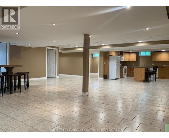 A spacious room with tile flooring and a bar area.