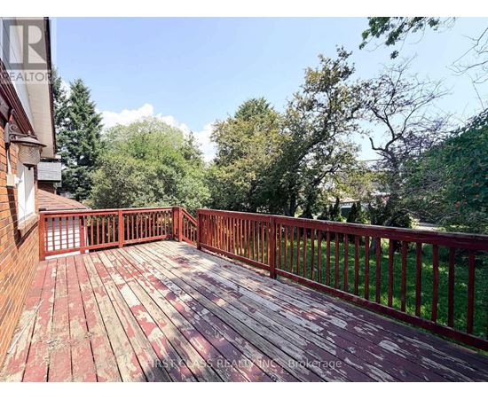 A wooden deck with a railing and trees in the background.