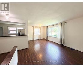 A room with wooden floors and white walls, with a window covered by curtains.