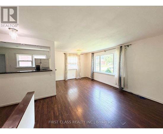A room with wooden floors and white walls, with a window covered by curtains.