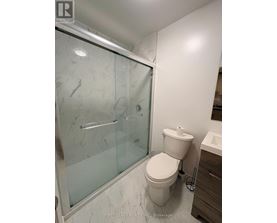 A white toilet in a bathroom with a glass shower door.
