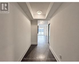 A long, narrow hallway with a light on the ceiling and a door at the end.