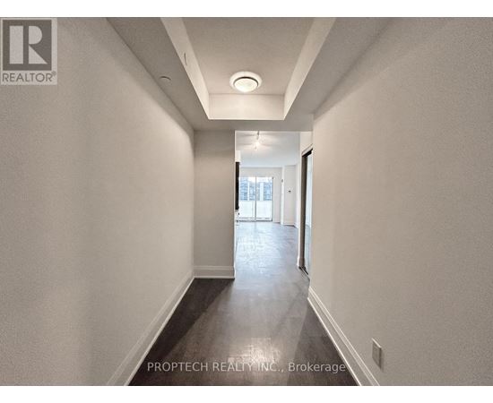 A long, narrow hallway with a light on the ceiling and a door at the end.