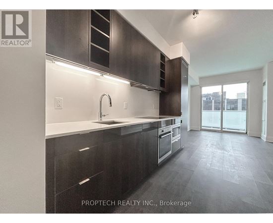 A modern kitchen with dark cabinets and a sink.