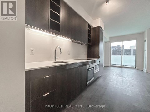 A modern kitchen with dark cabinets and a sink.