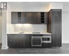 A modern kitchen with dark wood cabinets and stainless steel appliances.