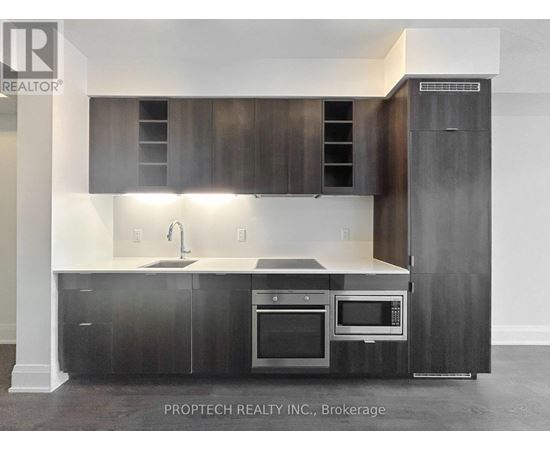 A modern kitchen with dark wood cabinets and stainless steel appliances.