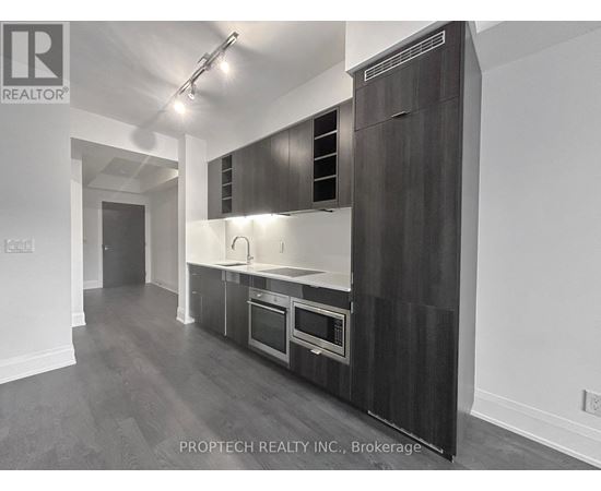 A modern kitchen with dark wood cabinets and stainless steel appliances.