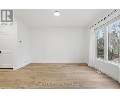 A room with a white door and a window with a view of trees outside.