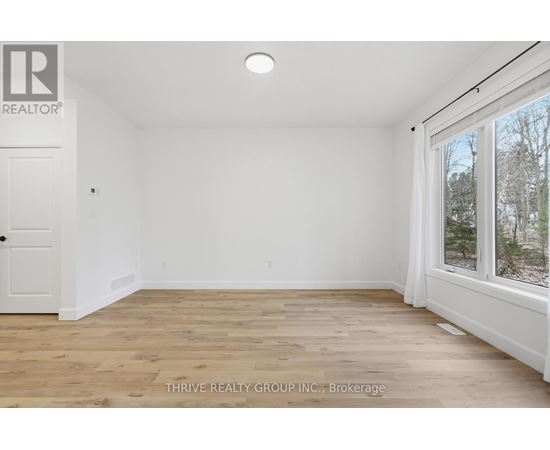 A room with a white door and a window with a view of trees outside.