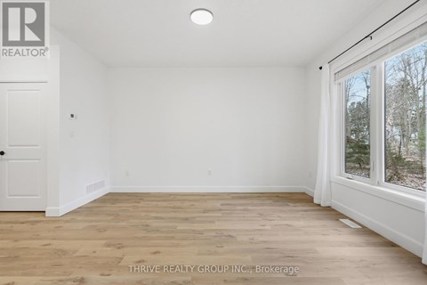 A room with a white door and a window with a view of trees outside.