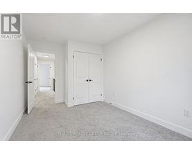 A white bedroom with a carpet floor and two doors.
