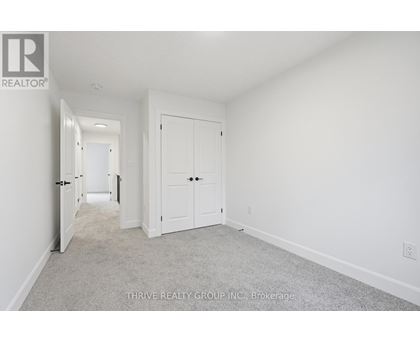 A white bedroom with a carpet floor and two doors.