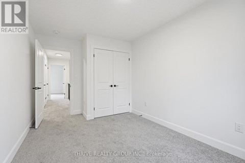A white bedroom with a carpet floor and two doors.
