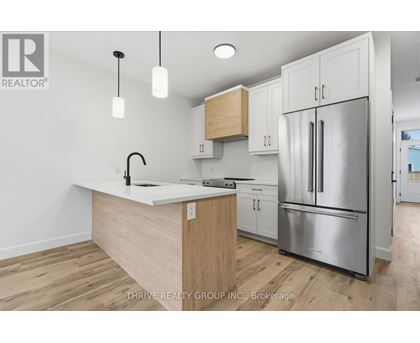 A kitchen with a white counter top and a stainless steel refrigerator.