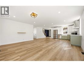 A spacious room with wooden flooring and a large window.