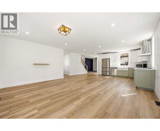 A spacious room with wooden flooring and a large window.