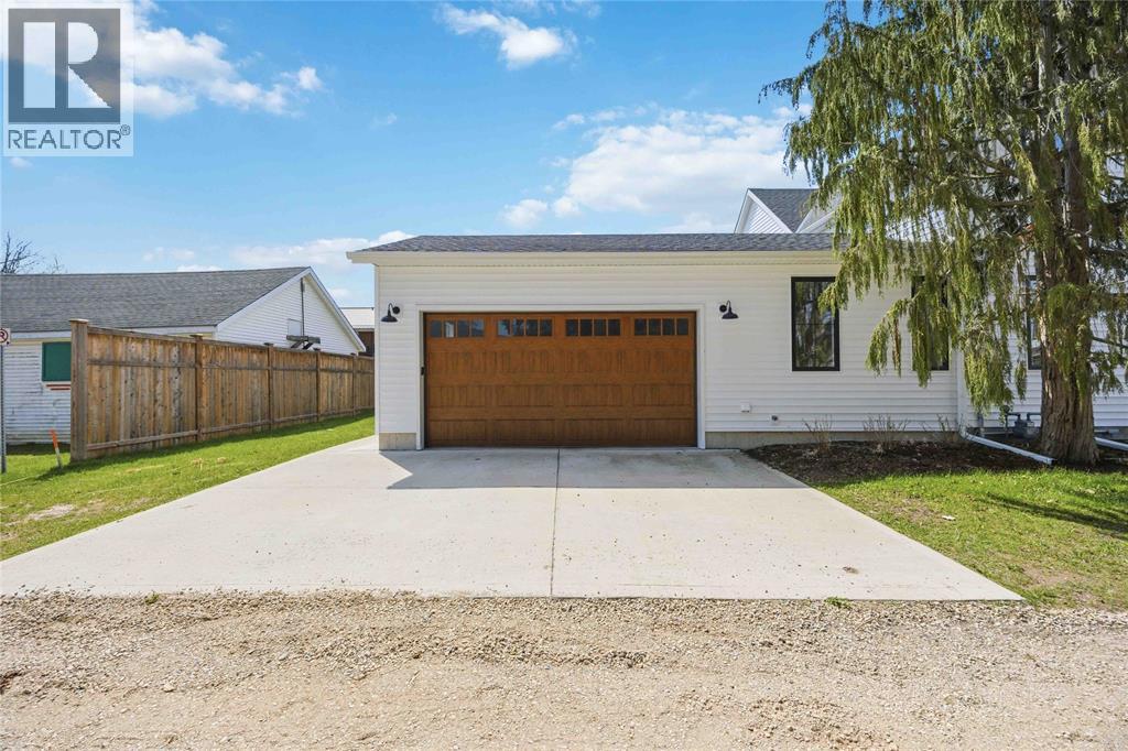 A white house with a brown garage door is for sale.