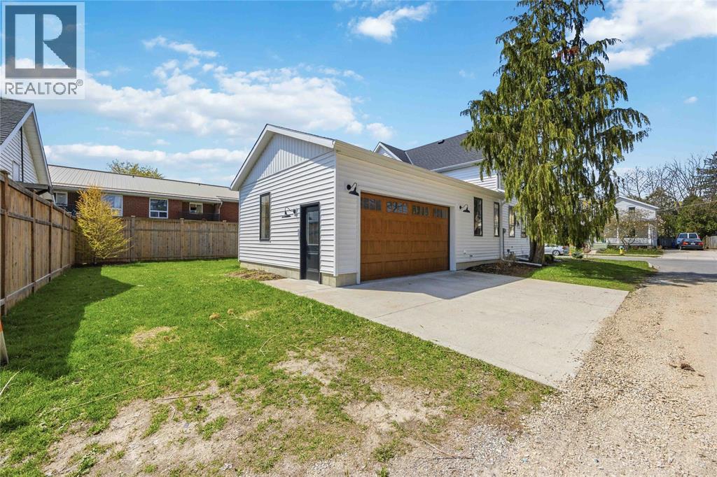 A residential property with a garage and a tree in front.