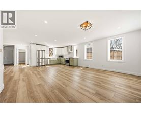 A spacious living room with wooden flooring and a large window.