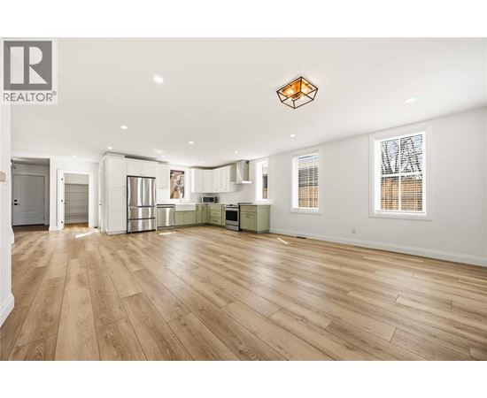 A spacious living room with wooden flooring and a large window.