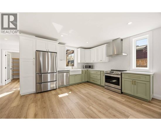 A kitchen with white cabinets and a wood floor.