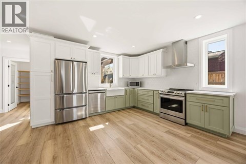 A kitchen with white cabinets and a wood floor.