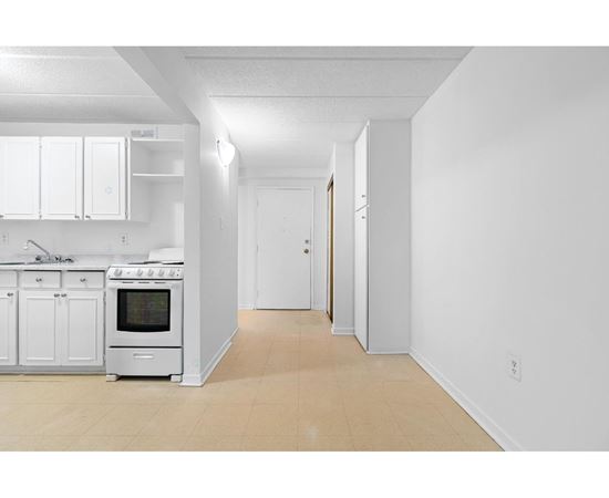 A white kitchen with a stove top oven and a white fridge.