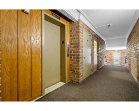 A hallway with wooden doors and brick walls.