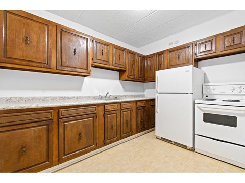 A kitchen with white appliances and wooden cabinets.