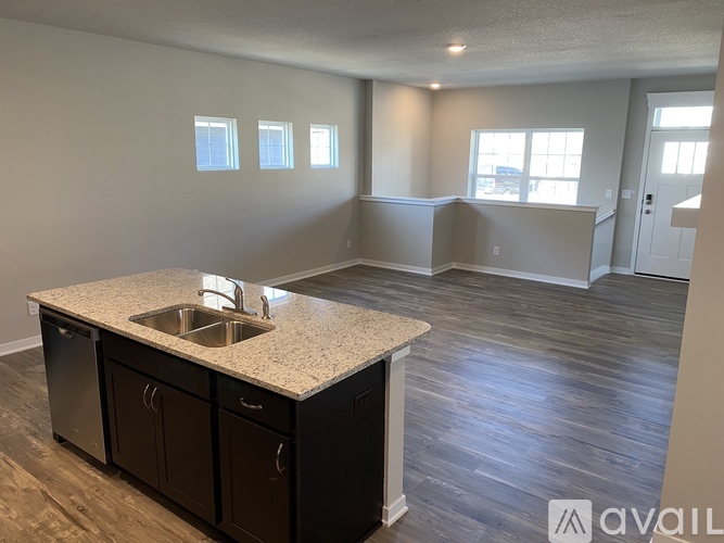 A kitchen with a sink and cabinets in a room with wood flooring.