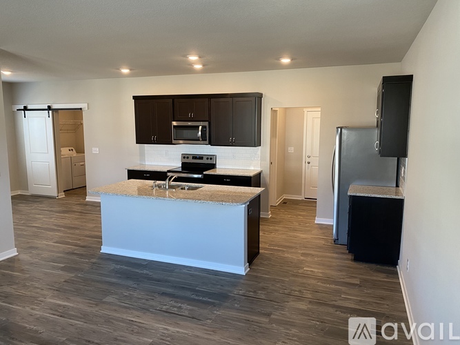 A kitchen with a white island and dark brown cabinets.
